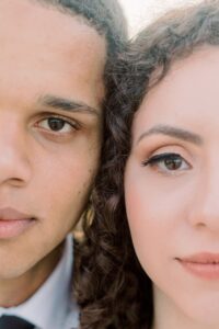 Close-up of two people with curly hair, neutral expressions, and half-visible faces before their New Orleans wedding.