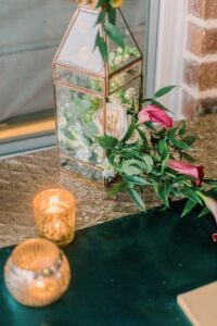 Glass lantern with flowers on gold cloth and two votive candles, creating an elegant Louisiana wedding ceremony setting.
