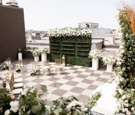 Rooftop wedding venue with checkered floor, white flowers, green foliage, and city views in New Orleans.