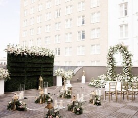 Rooftop wedding with gold chairs, floral arch, lanterns, candles, and city views for New Orleans ceremony inspiration.