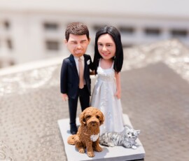 Bride and groom figurine with brown dog and gray-striped cat on a platform atop a textured glass table at a New Orleans wedding.
