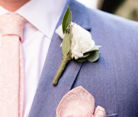 Man in a blue suit with pink paisley tie, pocket square, and white boutonniere—stylish New Orleans wedding inspiration.