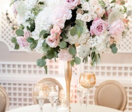 Elegant gold vase centerpiece with white and pink roses, hydrangeas, and greenery on a round table at a Louisiana wedding.