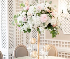 Tall gold vase with white and pale pink flowers, gold votives, and lattice walls—romantic Louisiana wedding inspiration.