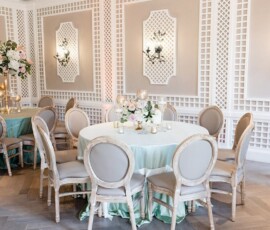 Wedding-ready dining room with mint-green tables, beige chairs, floral centerpieces, candles, and stylish lattice walls.