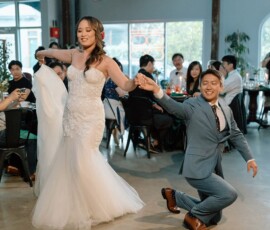 Joyful bride and groom dancing at their Louisiana wedding as guests seated at tables watch and smile.