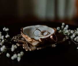 Gold rings and a diamond engagement ring on a white dish with baby’s breath flowers, elegant New Orleans wedding detail.