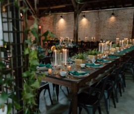 Rustic venue with brick walls and string lights, featuring long tables set for a formal New Orleans wedding reception.