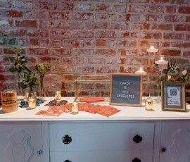 White dresser with red envelopes, candles, flowers, and a Cards & Red Envelopes sign against a red brick wall.