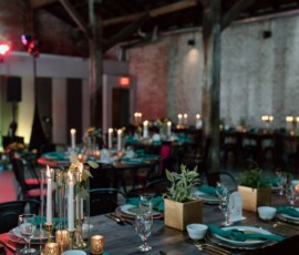 Rustic event space with wooden beams, brick walls, and candlelit tables set for a Gulf South wedding reception.