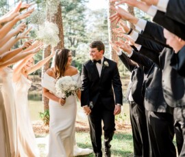 Bride and groom walk hand in hand under an arch of cheering bridesmaids and groomsmen at a joyful New Orleans wedding.