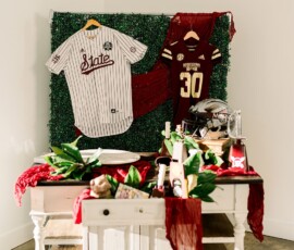 White table with greenery, sports jerseys, memorabilia, and red accents, inspired by a vibrant New Orleans wedding.