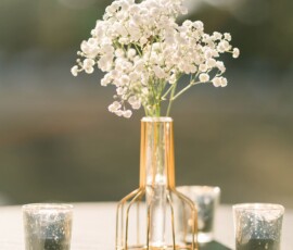 White flowers in a glass vase and two candle holders on a table, sunlight creating a warm, serene Louisiana wedding vibe.
