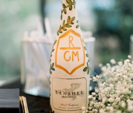 Banshee Brut California champagne bottle with baby’s breath and napkins on a black table at a Louisiana wedding reception.