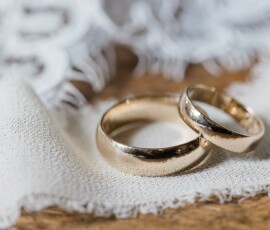 Gold wedding rings on white lace atop a wooden surface—an elegant Gulf South wedding scene.