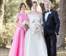 Bride in white gown with two smiling adults, holding bouquets outdoors under sunlight—Louisiana wedding inspiration.