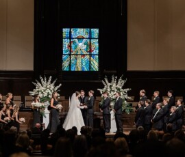 Gulf South church wedding with bride, groom, wedding party, guests, floral arrangements, and stained glass window.