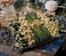 Silver tray of roasted asparagus, squash, and zucchini with flowers, crackers, and plates—an elegant Louisiana wedding spread.