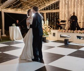 Bride and groom share their first dance on a checkered floor under string lights at a Louisiana wedding with live band.