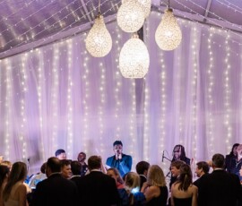 A band plays on stage under string lights as guests in formal attire dance at an elegant indoor Louisiana wedding.