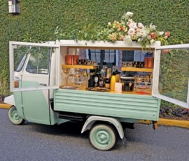 Mint-green three-wheeled mobile bar with bottles and flowers, parked by an ivy wall—Gulf South wedding inspiration.