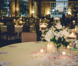 Banquet table with floral centerpiece, candles, and table 14 in a softly lit room with large windows and similar tables.