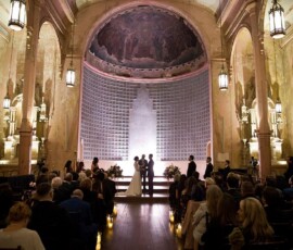 A couple weds at the altar of a grand Louisiana church, surrounded by guests and warm candlelit elegance.
