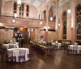 Chic event space with pink walls, tall ceilings, chandeliers, and elegant tables—perfect for New Orleans weddings.