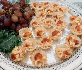 Silver tray with mini phyllo cups, cheese and sauce, red grapes, and leafy kale—ideal for wedding appetizers.
