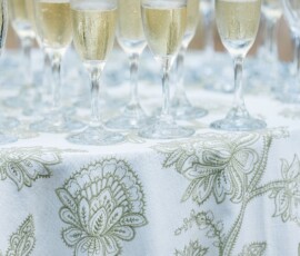 Champagne glasses on a green floral white tablecloth, perfect for classic Louisiana wedding inspiration.