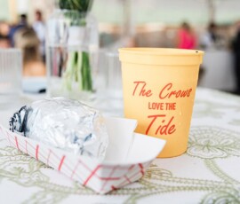 Foil-wrapped sandwich and yellow “The Crows LOVE THE Tide” cup on floral tablecloth; wedding inspiration scene.