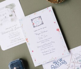 Wedding invitations, New Orleans map, ring box, and boutonniere on green—ideal Louisiana wedding inspiration.