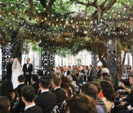 Outdoor Louisiana wedding under tree canopy and string lights, guests seated for a charming Southern celebration.