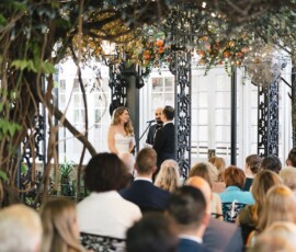 Bride and groom exchange vows under a decorated gazebo at an outdoor New Orleans wedding surrounded by greenery.