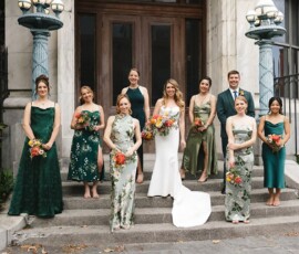 Bride and wedding party in green, white, and floral dresses pose with bouquets on stone steps at a joyful Louisiana wedding.
