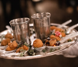 Silver tray with metal cups and ceramic spoons serving fried appetizers, garnished with microgreens.