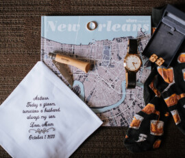 Map of New Orleans with a watch, wooden pen, beer socks, cufflinks, and a personalized handkerchief dated October 7, 2023.