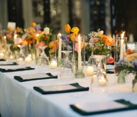 Elegant long dining table with white cloth, glassware, candles, and colorful flowers—ideal for a formal New Orleans wedding.