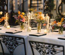 Elegant New Orleans wedding table with white cloth, flowers, candles, black chairs, and string lights for a warm celebration.