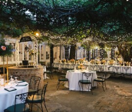 New Orleans courtyard wedding with round tables, white linens, florals, and string lights under a gazebo for a magical vibe.