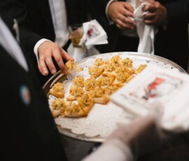 Server with silver tray of hors d’oeuvres greets formally dressed guests at an elegant Louisiana wedding reception.