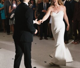 Bride and groom dance joyfully as guests watch and take photos at a bright, elegant Louisiana wedding.