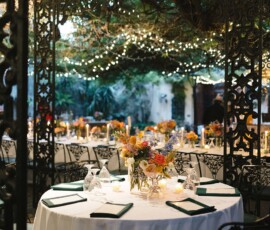 Elegant round table with white cloth, floral centerpiece, green napkins, and string lights—ideal Gulf South wedding decor.