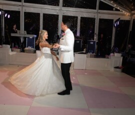 Bride and groom dance on pink and white checkered floor under string lights at their Louisiana wedding reception.