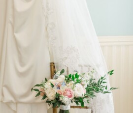 White lace veil over a chair with pink and white bouquet in glass vase and bridal shoes—New Orleans wedding inspiration.