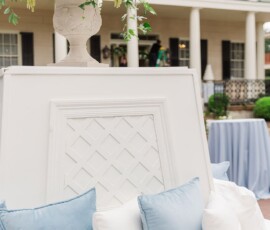 Blue and white pillows on a white bench with floral decor, perfect for an elegant Louisiana wedding setting.