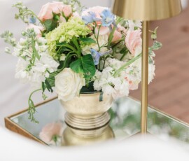 Gold vase with colorful flowers on a mirrored table beside a modern gold lamp—ideal for elegant New Orleans weddings.
