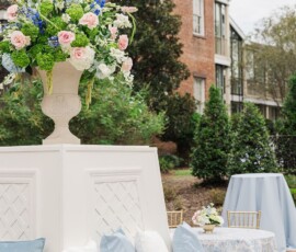 Outdoor seating with white and blue cushions, floral centerpiece, round table, and historic brick building—ideal for Louisiana weddings.