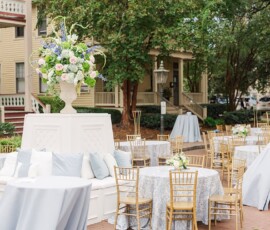 Outdoor New Orleans wedding with light blue tables, gold chairs, floral centerpiece, and historic house backdrop.