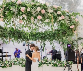Bride and groom share their first dance under a floral canopy at a Louisiana wedding with live band and lush flowers.